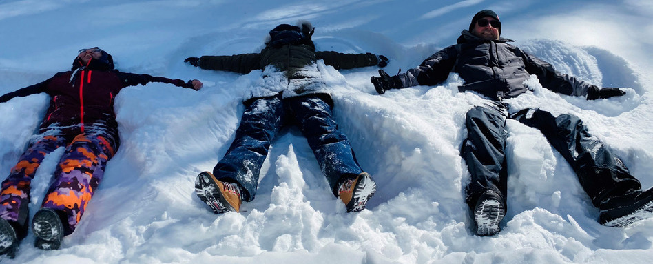Three people make snow angels on a sunny day. Three people make snow angels on a sunny day.