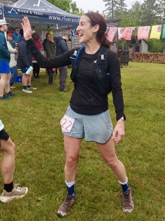Chrissy gives a high five to someone out of frame after a marathon.