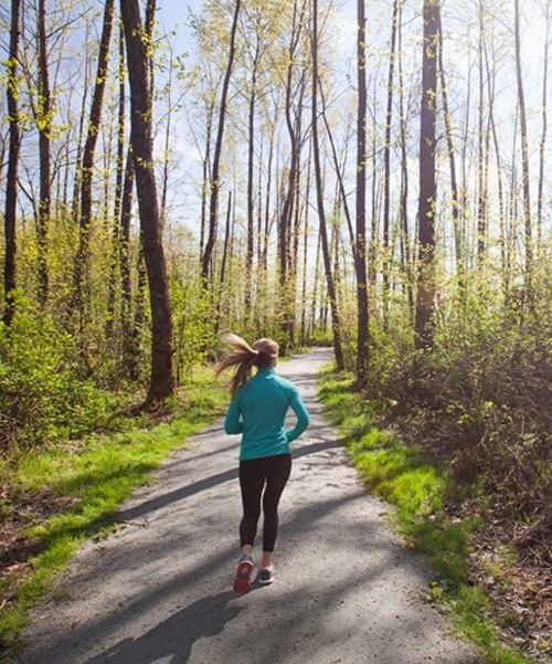 A person in athletic gear runs along a forested trail.